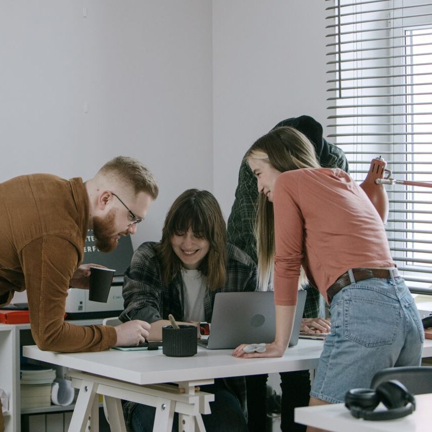 Young professionals brainstorming and sharing ideas at a desk in a contemporary office.